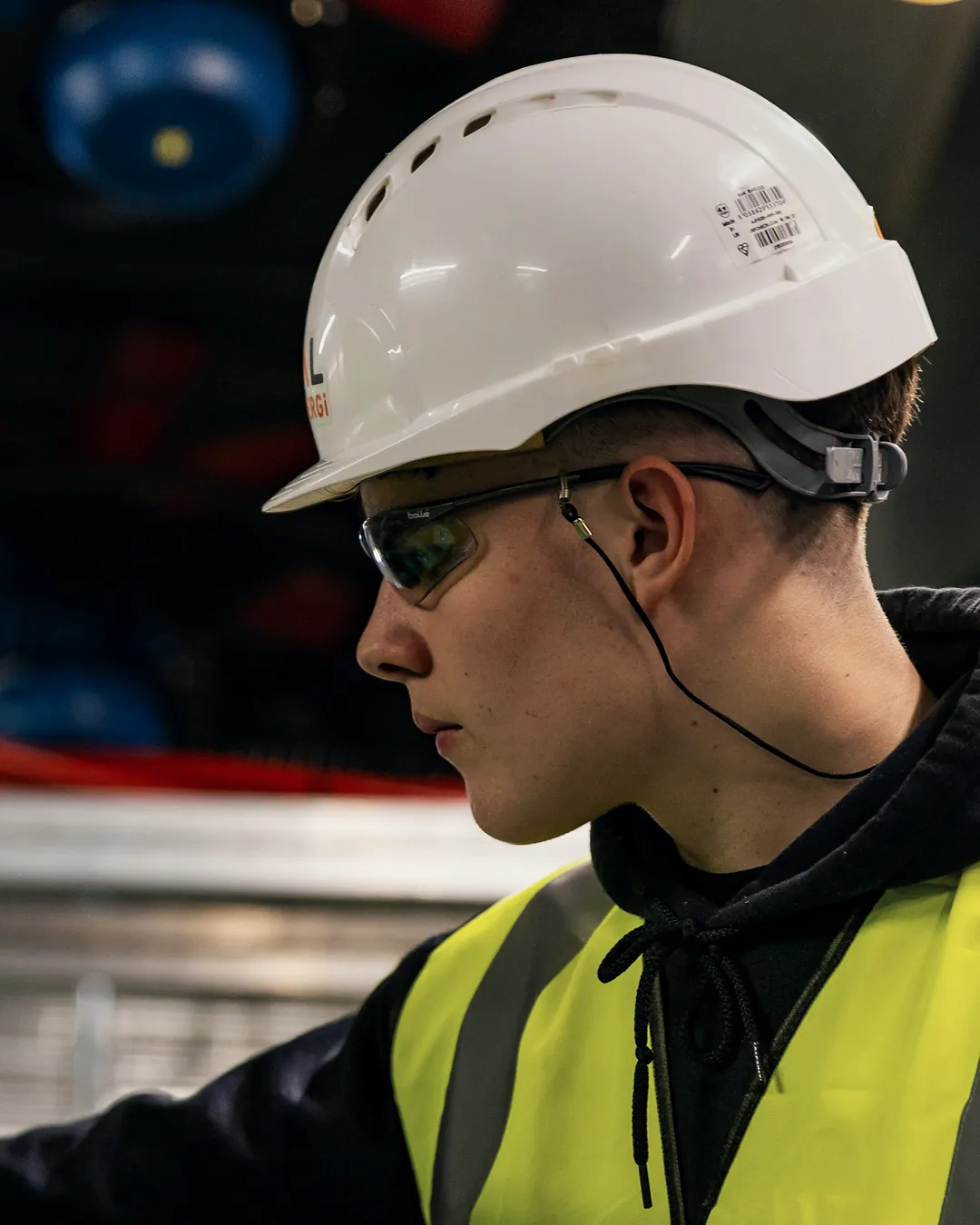 An energy technician in a hard hat and safety glasses at work on the equipment