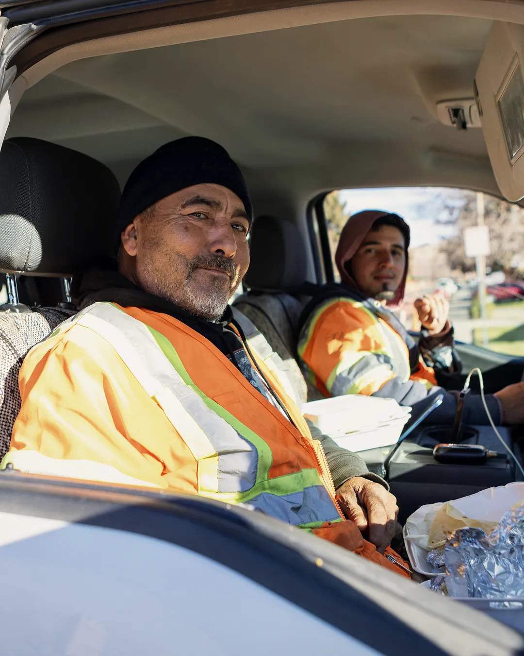Two field crew members in high-visibility jackets in the cab of their pickup