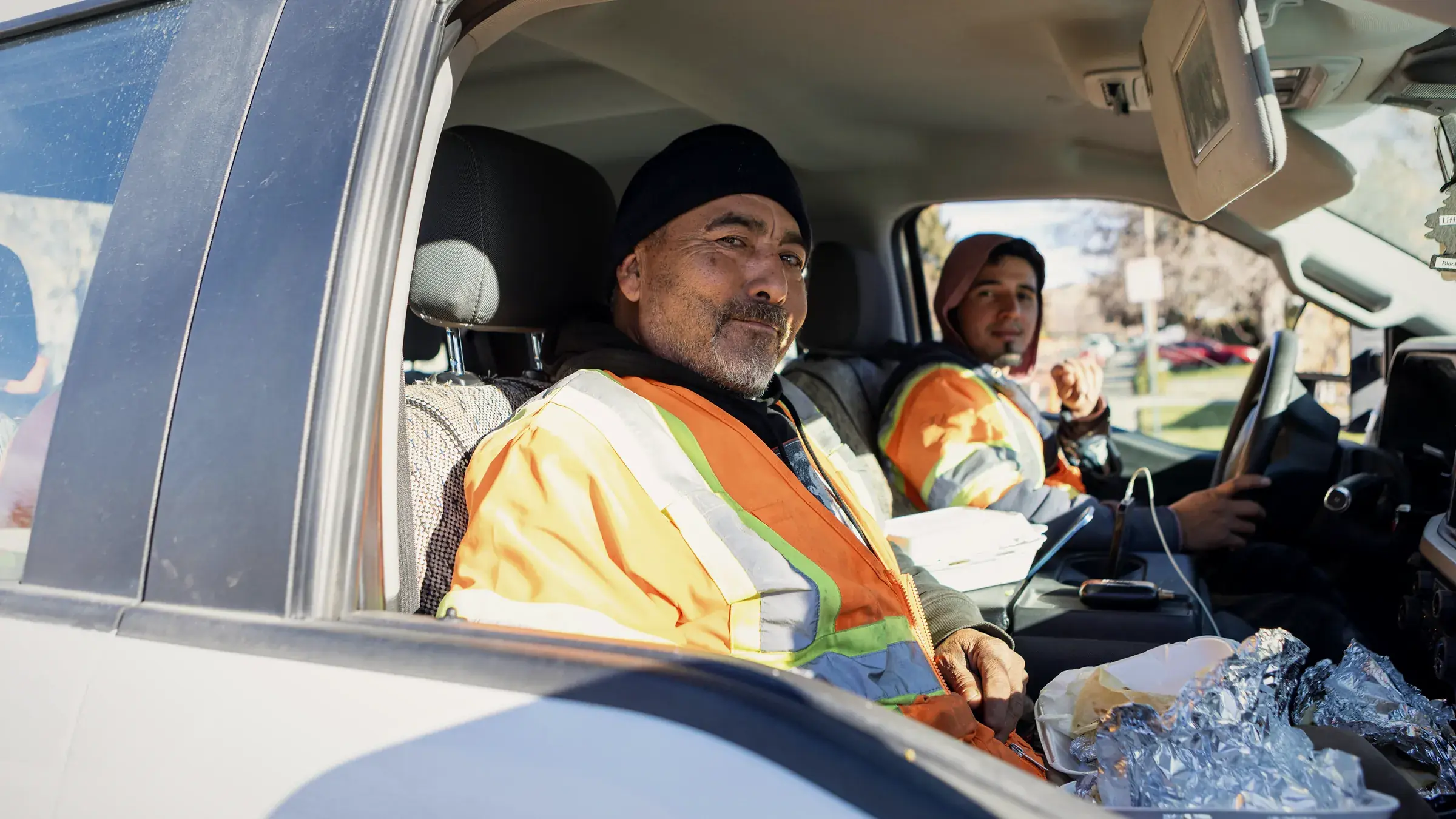 Two field crew members in high-visibility jackets in the cab of their pickup
